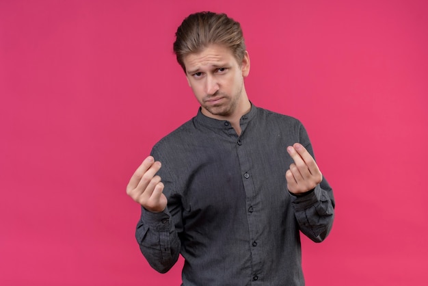 Young handsome man making money gesture with arms with skeptic expression