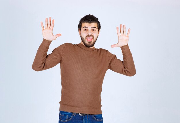 A young handsome man model looking and raising his hands .