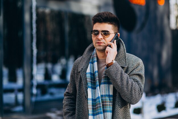 Молодой красивый мужчина на улице с помощью телефона
