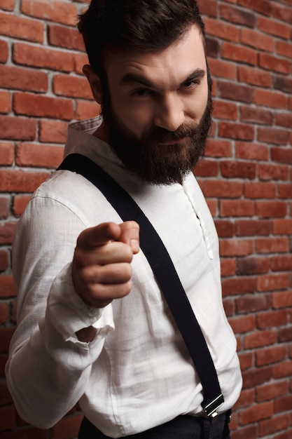 Free photo young handsome man pointing finger on brick wall.