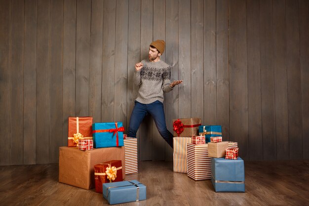 木製の壁を越えてクリスマスプレゼントの中でポーズをとって若いハンサムな男