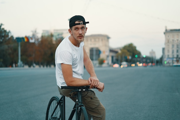 Young handsome man posing while sitting on bike