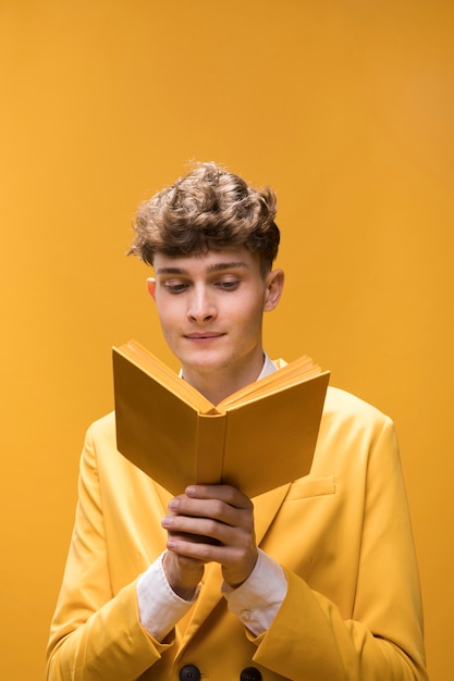 Young handsome man reading a book in a yellow scene