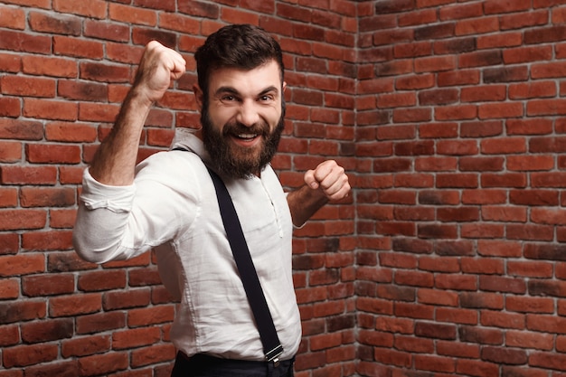 Young handsome man rejoicing posing on brick wall.