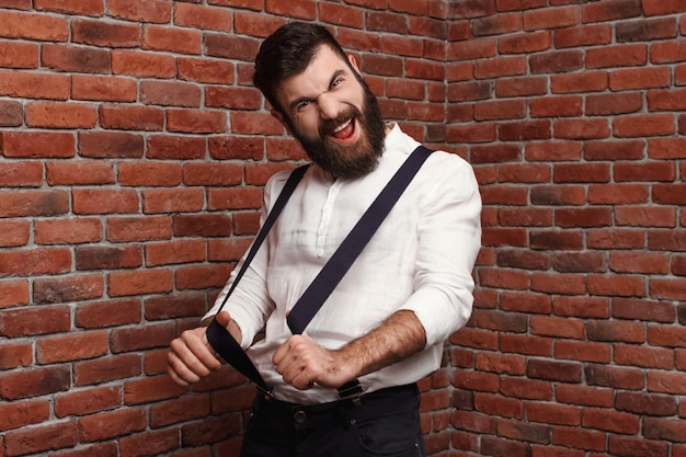 Young handsome man rejoicing posing on brick wall.