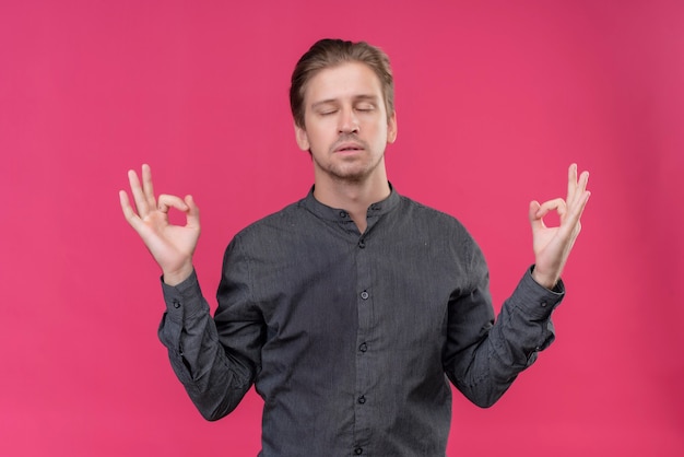 Free photo young handsome man relaxing with closed eyes making meditation gesture