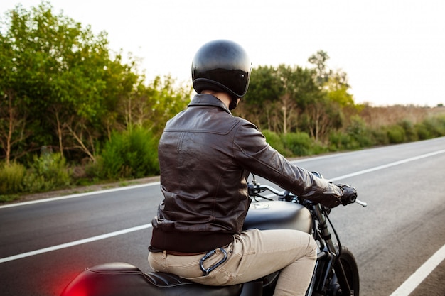 Free photo young handsome man riding on motorbike at countryside road.