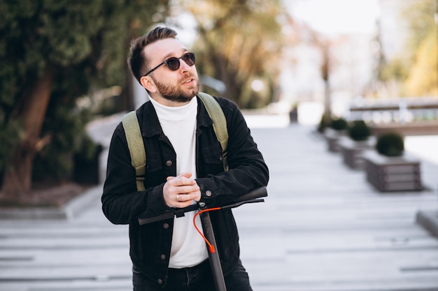 Young handsome man riding on scooter in the park