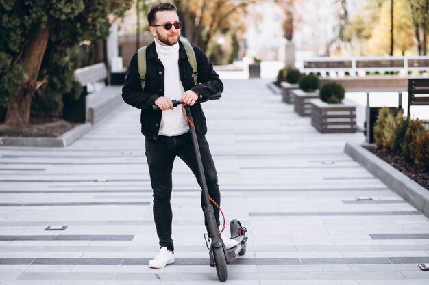 Giovane uomo bello che guida su scooter nel parco