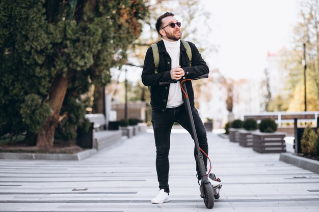 Young handsome man riding on scooter in the park