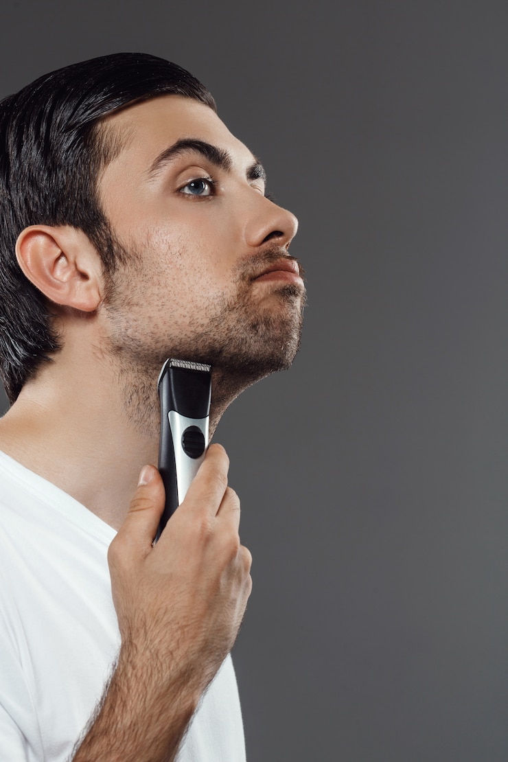 Free Photo young handsome man shaving over grey wall.