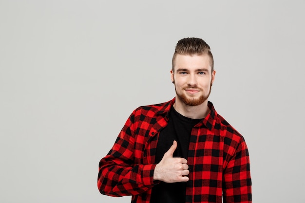 Young handsome man showing okay over grey wall.