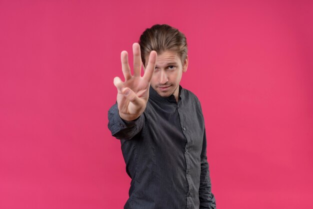 Free photo young handsome man showing and pointing up with fingers number three