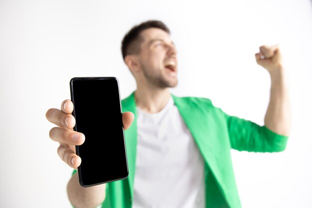 Young handsome man showing smartphone screen and signing OK sign isolated on gray