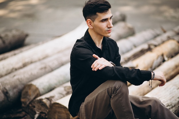 Young handsome man sitting on log in the park