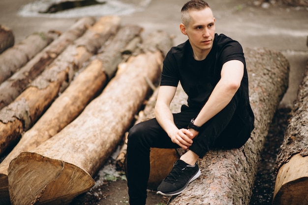 Young handsome man sitting on a log in park