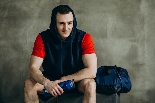 Giovane uomo bello in abiti sportivi in palestra