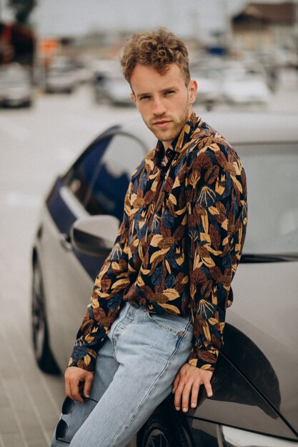 Young handsome man standing by car