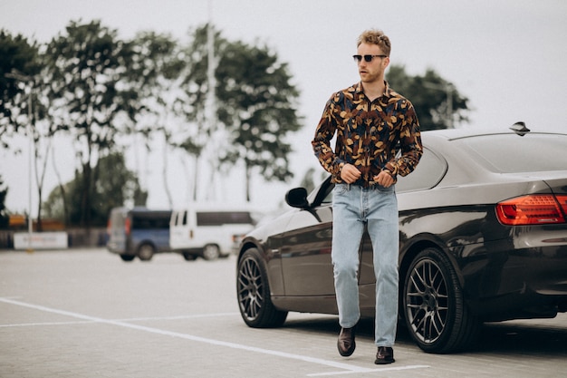 Free photo young handsome man standing by car