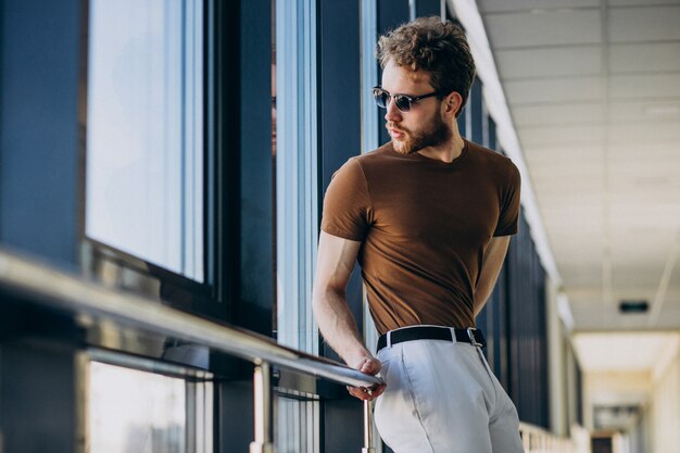 Young handsome man standing by the window at the airport