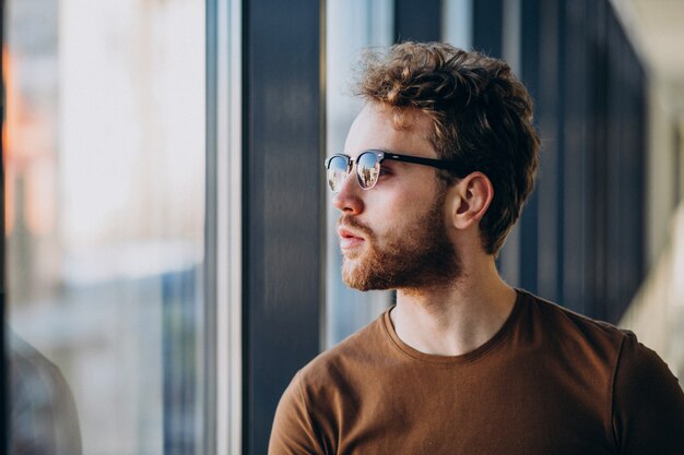 Young handsome man standing by the window at the airport