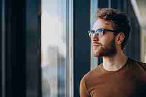 Free photo young handsome man standing by the window at the airport