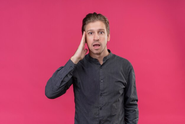 Young handsome man standing with hand on head for mistake