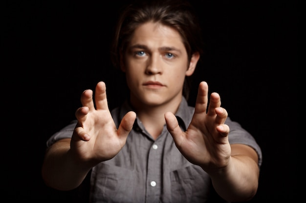 Young handsome man stretching hands to camera