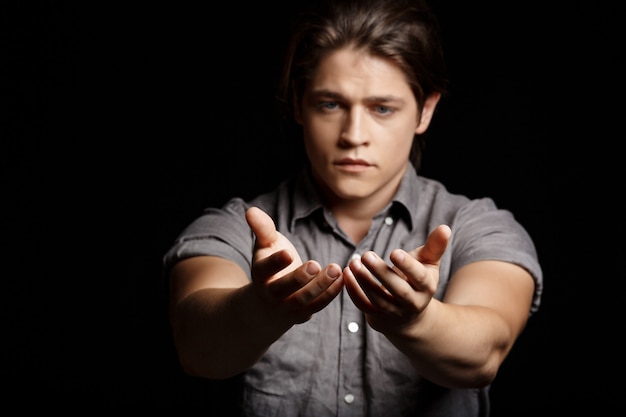 Young handsome man stretching hands to camera