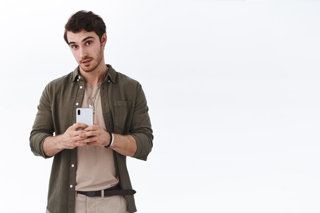 Young handsome man taking photo, holding smartphone