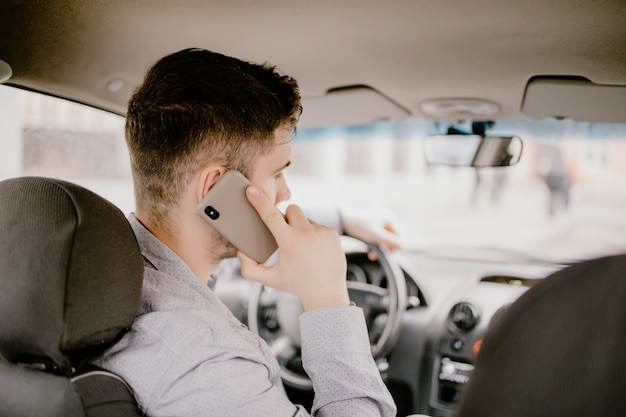 잘 생긴 젊은이 운전 및 추월하는 동안 휴대 전화에 대 한 얘기도 및 교통에주의.