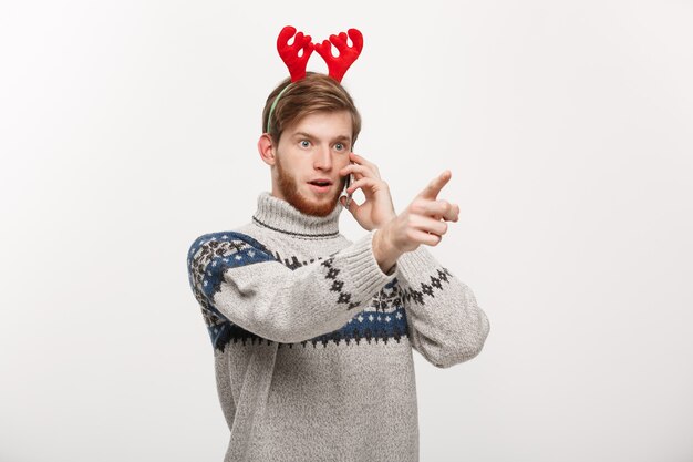 Young handsome man talking on phone and pointing finger in front.