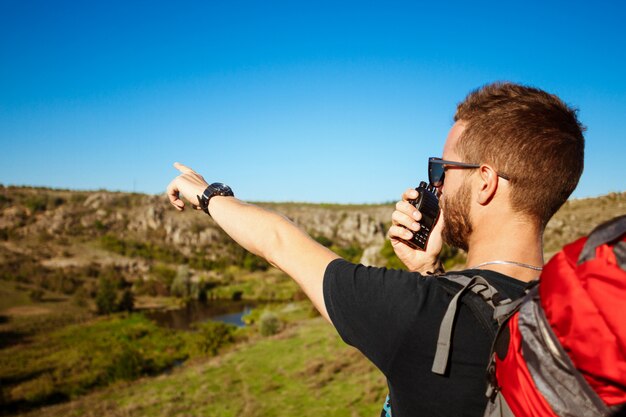 Young handsome man talking on walkie talkie radio, enjoying canyon view