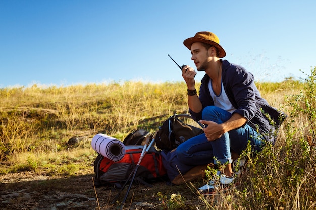 Young handsome man talking on walkie talkie radio, enjoying canyon view