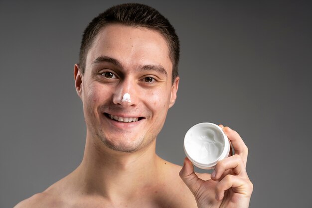 Young handsome man using a cream for acne