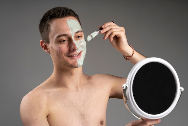 Foto gratuita giovane uomo bello utilizzando una maschera per l'acne