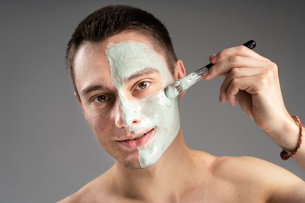 Young handsome man using a mask for acne