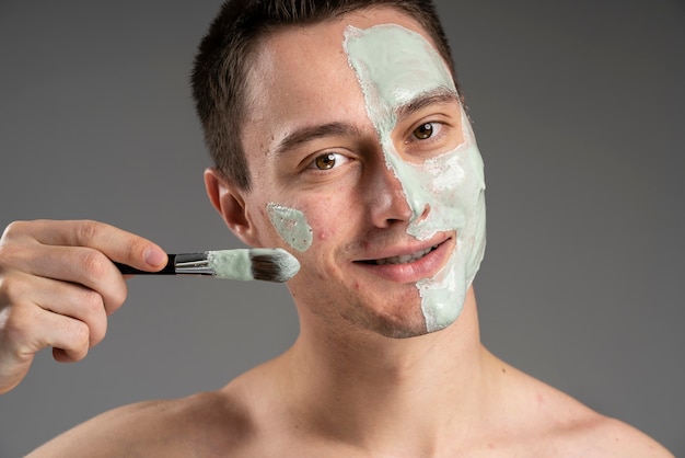 Giovane uomo bello utilizzando una maschera per l'acne