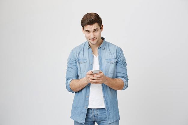 Young handsome man using mobile phone, looking