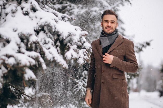 Young handsome man walking in a winter forest