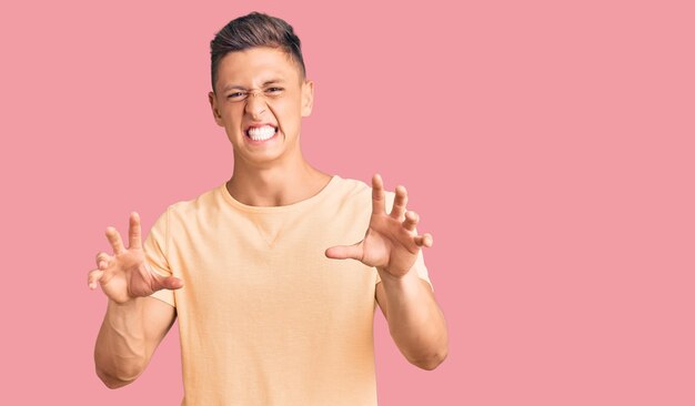 Young handsome man wearing casual clothes smiling funny doing claw gesture as cat aggressive and sexy expression