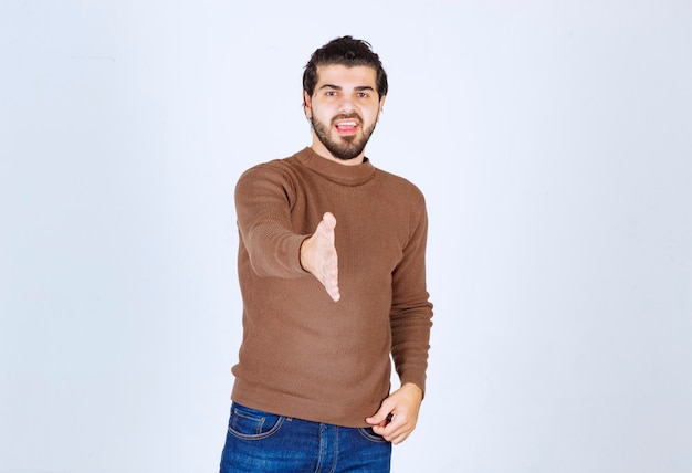 Young handsome man wearing casual sweater over isolated white background smiling cheerful offering palm hand giving assistance and acceptance. high quality photo