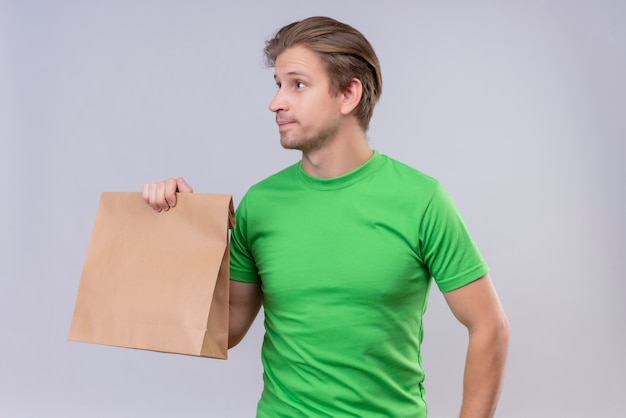 Young handsome man wearing green t-shirt holding paper package