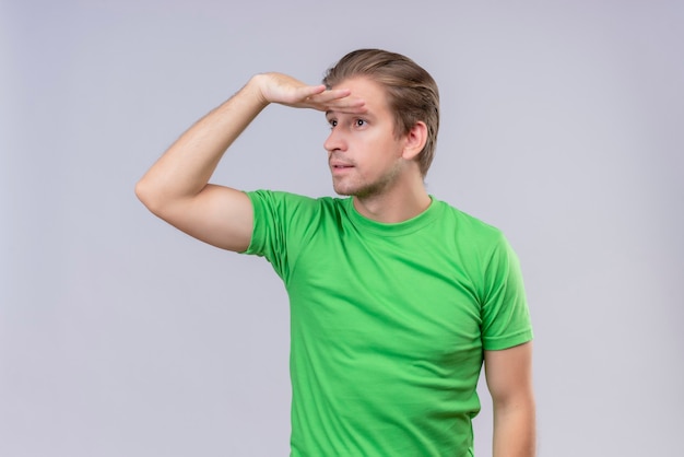 Free photo young handsome man wearing green t-shirt looking far away