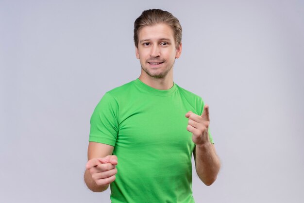 Young handsome man wearing green t-shirt pointing with fingers