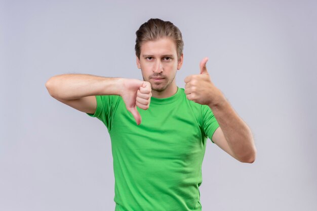 Young handsome man wearing green t-shirt with serious expression on face