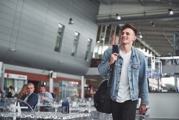 Young handsome man with a bag on his shoulder in a hurry to the airport.