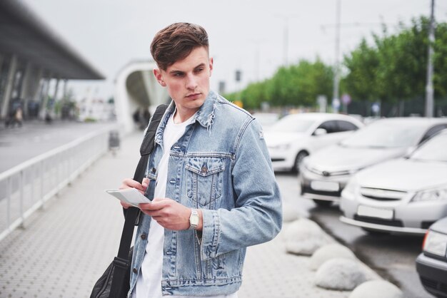 Young handsome man with a bag on his shoulder in a hurry to the airport.