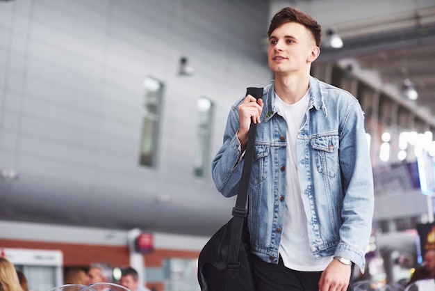 Young handsome man with a bag on his shoulder in a hurry to the airport.