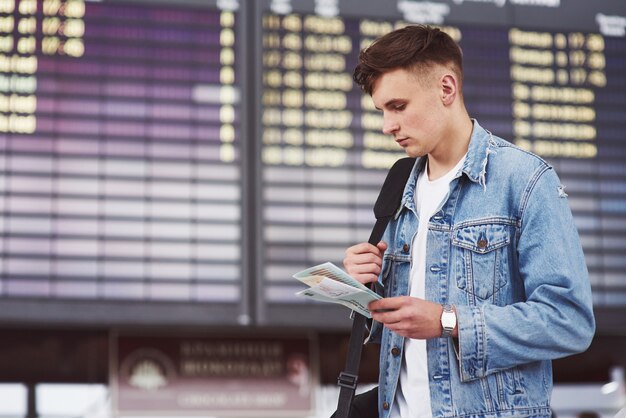 空港に急いで彼の肩にバッグを持つ若いハンサムな男。